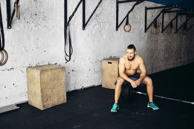 Uomo grazioso stanco dopo il sollevamento pesi in palestra