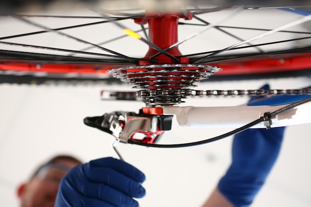 Uomo guantato che ripara la ruota di bicicletta con la chiave della casa