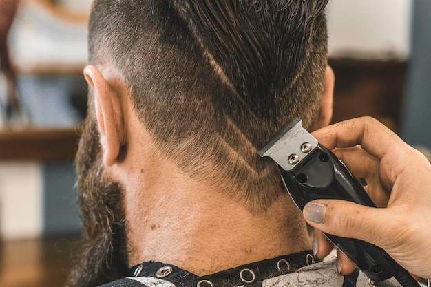 Uomo hipster al salone del barbiere che si fa tagliare barba e capelli