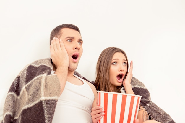 Uomo impaurito e donna che guardano film horror con popcorn