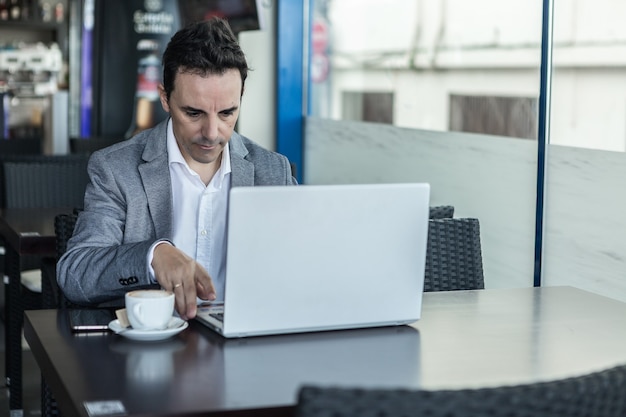 Uomo impegnato che lavora con il computer portatile nella caffetteria