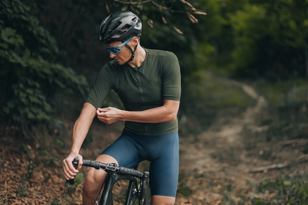 Uomo in abiti sportivi che si preparano per andare in bicicletta al parco verde