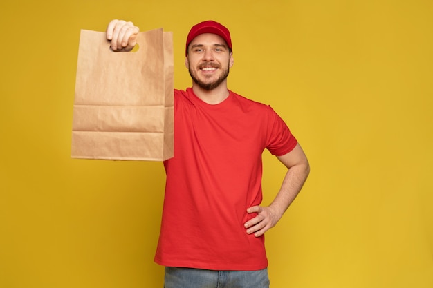 Uomo in berretto rosso, t-shirt che dà ordine di fast food isolato sulla parete gialla