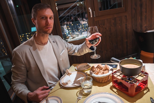 Uomo in blazer beige che si gode una cena di fondue in un accogliente ristorante alpino