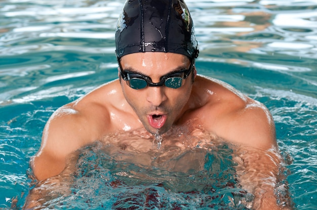 Uomo in buona salute che nuota con sforzo in piscina