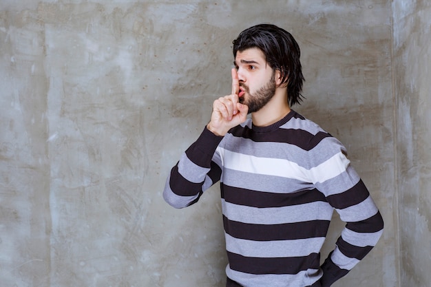 Uomo in camicia a righe che chiede silenzio