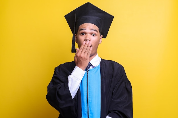 uomo in cappello di laurea e abito da cerimonia spaventato e scioccato sorpresa ed espressione stupita