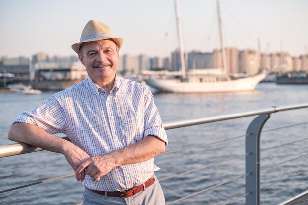 Uomo in cappello estivo in piedi vicino al mare in una soleggiata giornata estiva