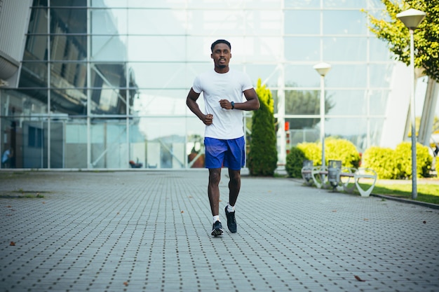 Uomo in corsa mattutina, giovane atleta afroamericano che corre vicino allo stadio