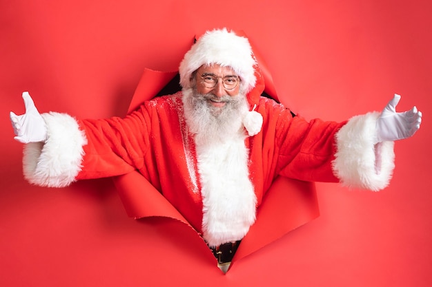 Uomo in costume da Babbo Natale che esce attraverso la carta