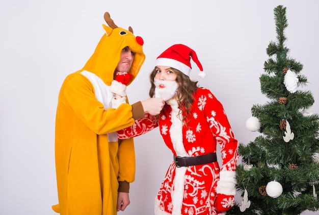 uomo in costume da cervo e donna in costume di Babbo Natale vicino all'albero di Natale