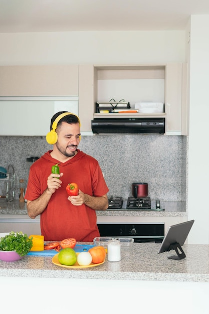 Uomo in cucina che prepara una ricetta seguendo i passaggi guardando il suo tablet