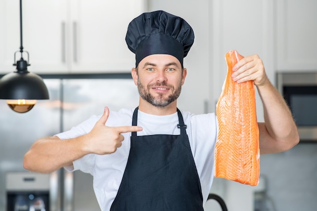 Uomo in cucina moderna che prepara cibo sano pesce salmone bell'uomo sta cucinando pesce fresco salmone b