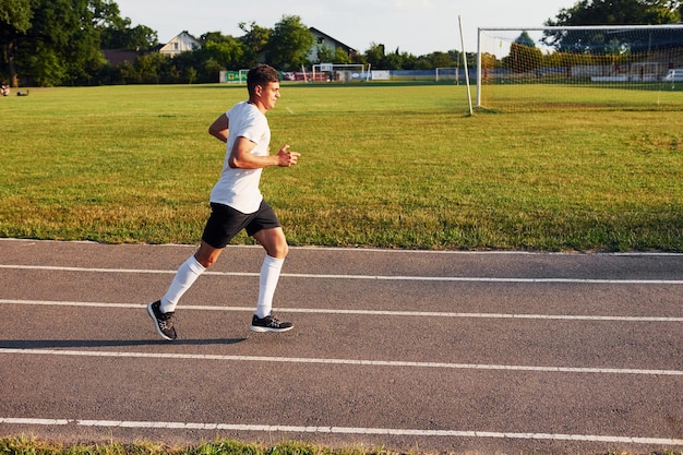 Uomo in divisa sportiva che corre in pista di giorno