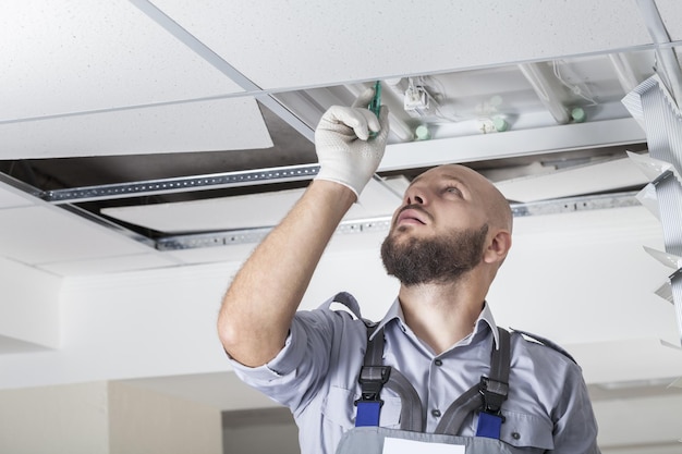 Uomo in elmetto che installa il condizionatore d'aria sulla facciata dell'edificio