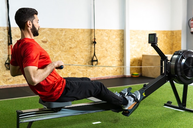 Uomo in forma che si allena sul vogatore in palestra