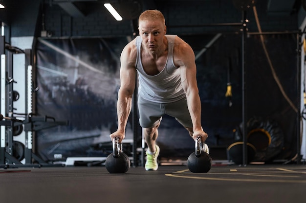 Uomo in forma e muscoloso che fa flessioni orizzontali con barre in palestra