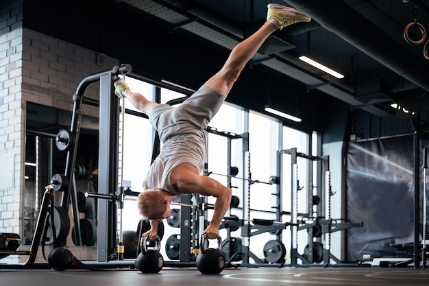 Uomo in forma e muscoloso che fa flessioni verticali con i manubri in palestra.