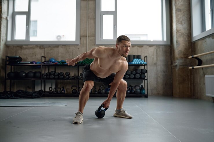 Foto uomo in forma e muscoloso che solleva la campana del bollitore durante la lezione di ginnastica in palestra