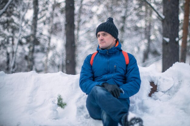 Uomo in giacca invernale che cammina nella foresta nevosa di inverno giorno di inverno nevoso