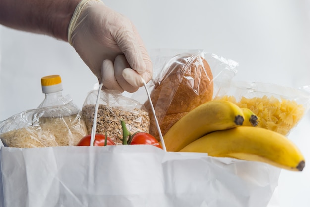 Uomo in guanti di gomma che tengono il sacco di carta con il cibo