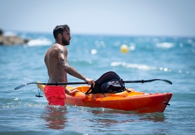 Uomo in kayak sulla spiaggia durante le vacanze estive