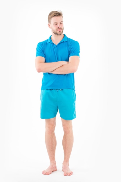 Uomo in maglietta e pantaloncini a piedi nudi isolato su sfondo bianco Uomo barbuto con gli occhi chiusi in abiti blu Macho in abbigliamento attivo per l'allenamento Stile e tendenza moda sportiva Attività fitness e palestra