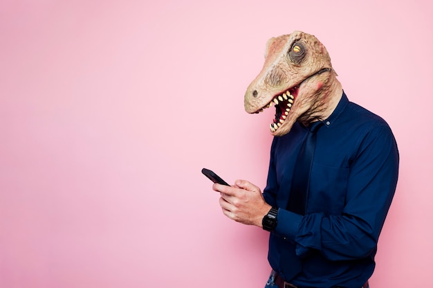 Uomo in maschera di dinosauro che utilizza smartphone