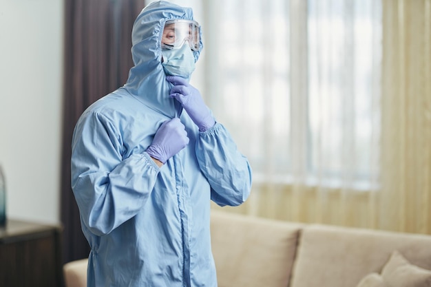 Uomo in maschera e occhiali durante la disinfezione nella stanza