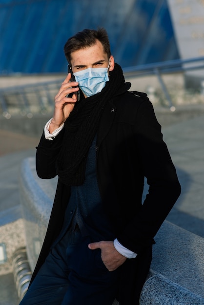 Uomo in maschera facciale all'aperto parlando al telefono