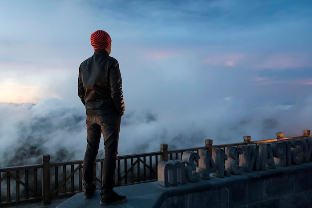 Uomo in montagna guardando in lontananza Giovane viaggiatore in piedi e guardando la vista della natura a Sapa Vietnam nella stagione delle piogge Tramonto su Fansipan