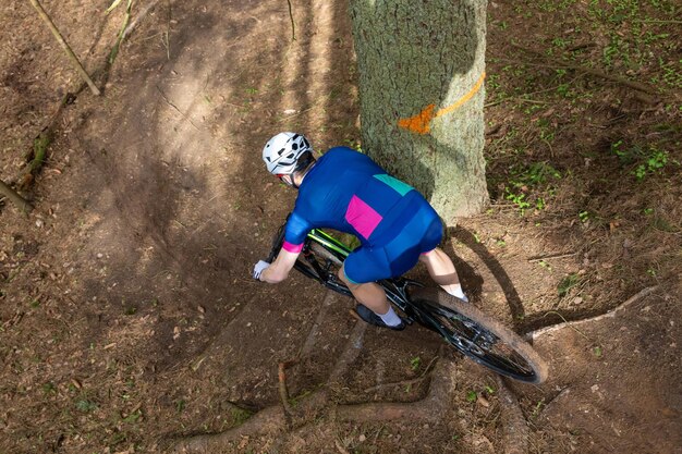 Uomo in mountain bike attraverso una zona boscosa in una giornata estiva Il mountain biker scende attraverso una foresta bruciata sulla pista con le radici