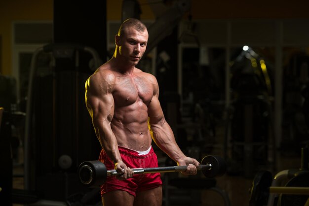 Uomo In Palestra Che Esercitano I Bicipiti Con Il Bilanciere