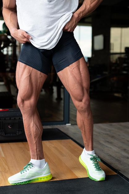 Uomo in palestra che mostra il suo primo piano ben allenato delle gambe