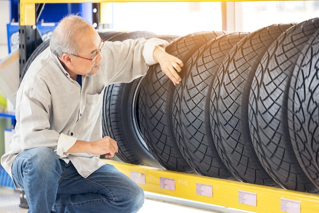 Uomo in pensione che tocca e sceglie di comprare un pneumatico in un supermercato che misura un'auto in gomma