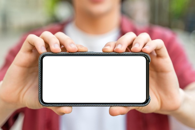 Uomo in piedi all'aperto e tenendo il telefono con lo schermo bianco vuoto in mano