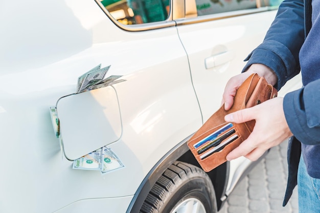 Uomo in piedi con il portafoglio vuoto dollari soldi nel serbatoio dell'auto gas s