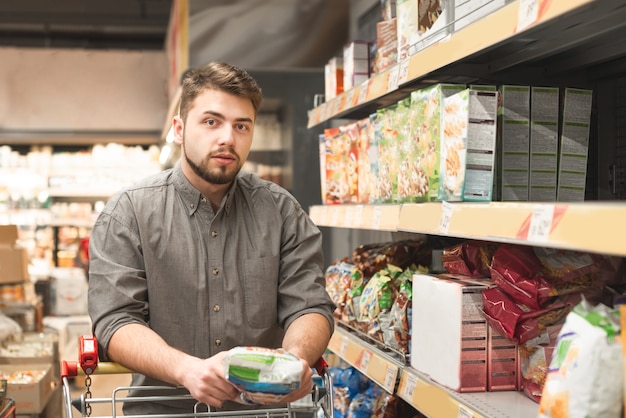 Uomo in piedi con un carrello sul corridoio in un supermercato