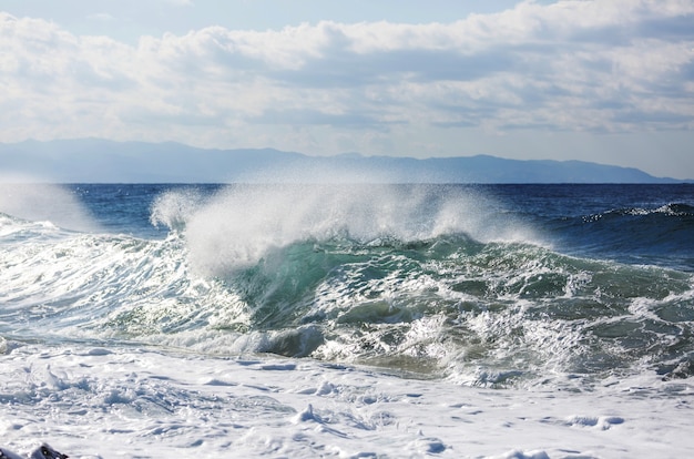 Uomo in piedi contro il mare su un molo con grande onda che batte con schizzi in una tempesta