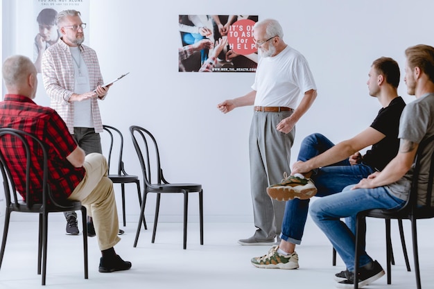 Uomo in piedi davanti a un gruppo durante la sessione di psicoterapia