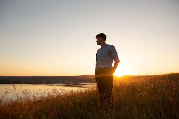 Uomo in piedi e godersi il bellissimo tramonto su un'ampia valle del fiume.