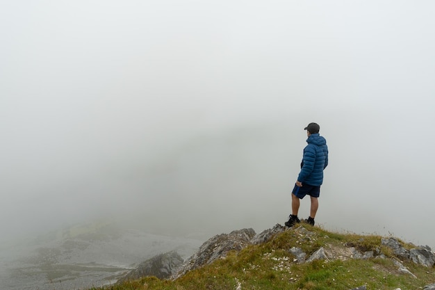 Uomo in piedi in cima alla montagna ammirando il paesaggio con la nebbia