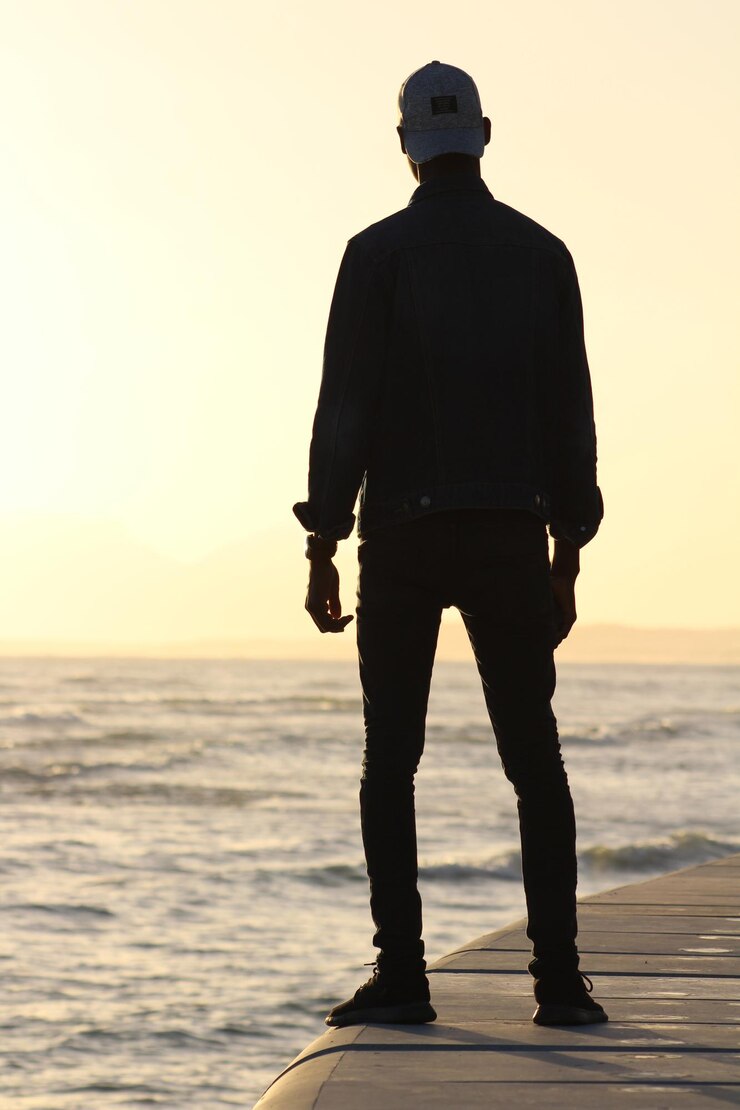 Foto uomo in piedi su un muro di sostegno contro il mare durante il tramonto
