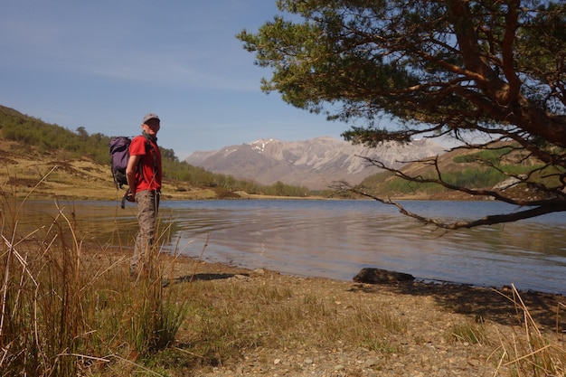 Uomo in piedi sul campo vicino al fiume contro il cielo
