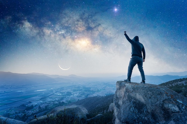 Uomo in piedi sulla cima della montagna vista posteriore con una mano che celebra