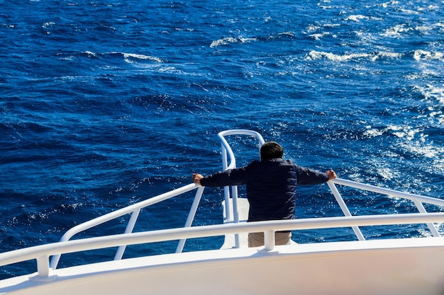 Uomo in piedi sulla prua bianca dello yacht e guardando il mare o l'oceano Concetto di vacanza di lusso Vista posteriore