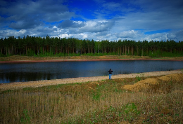 Uomo in piedi sullo sfondo della riva del fiume estivo