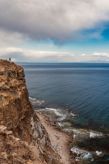 Uomo in piedi vicino al bordo della scogliera con splendida vista sul mare