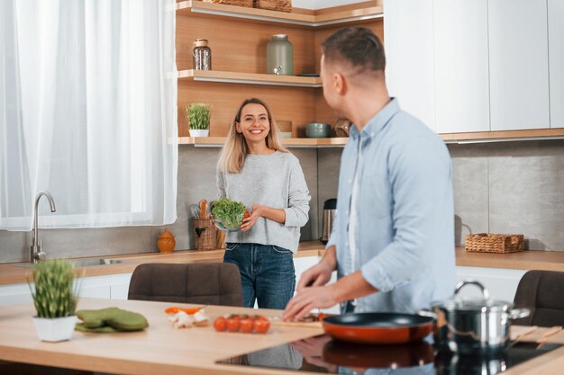 Uomo in piedi vicino al tavolo Coppia che prepara il cibo a casa sulla cucina moderna