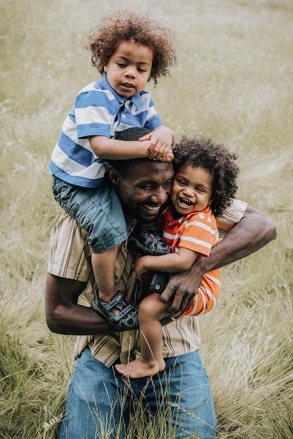 uomo in polo a righe bianche e blu che trasporta il bambino in marsupio arancione e nero Famiglia nera